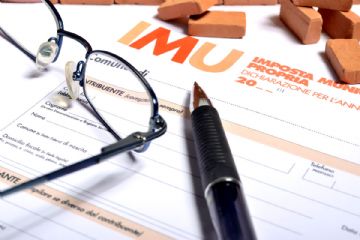 foglio di dichiarazione imu, paio di occhiali, penna e mattoncini